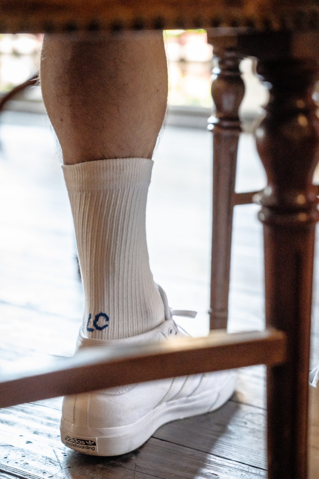A Landfeel Club sock with the LC logo on the heel, under a café table